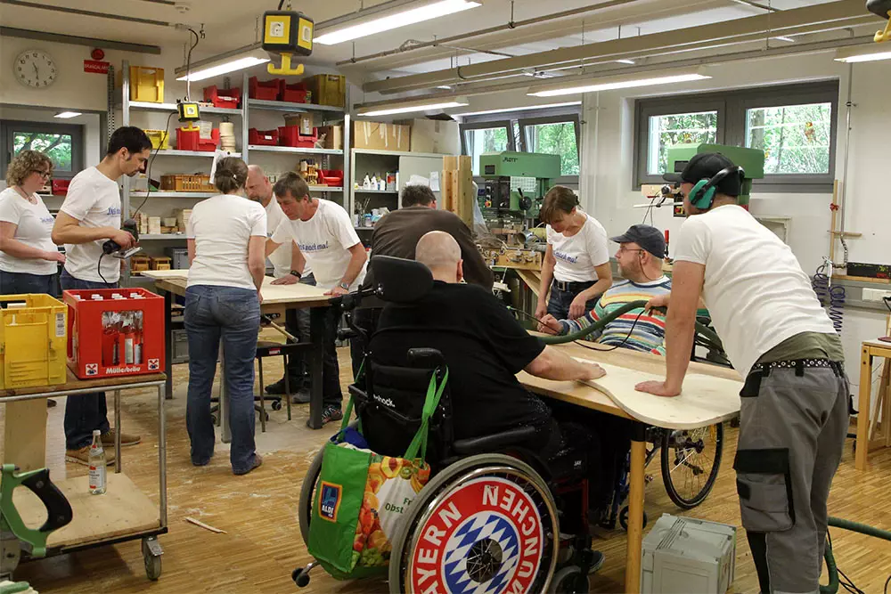 Mitarbeiter von Energie Südbayern bauen beim Social Day München mit behinderten Menschen in der Holzwerkstatt Sonnenliegen.